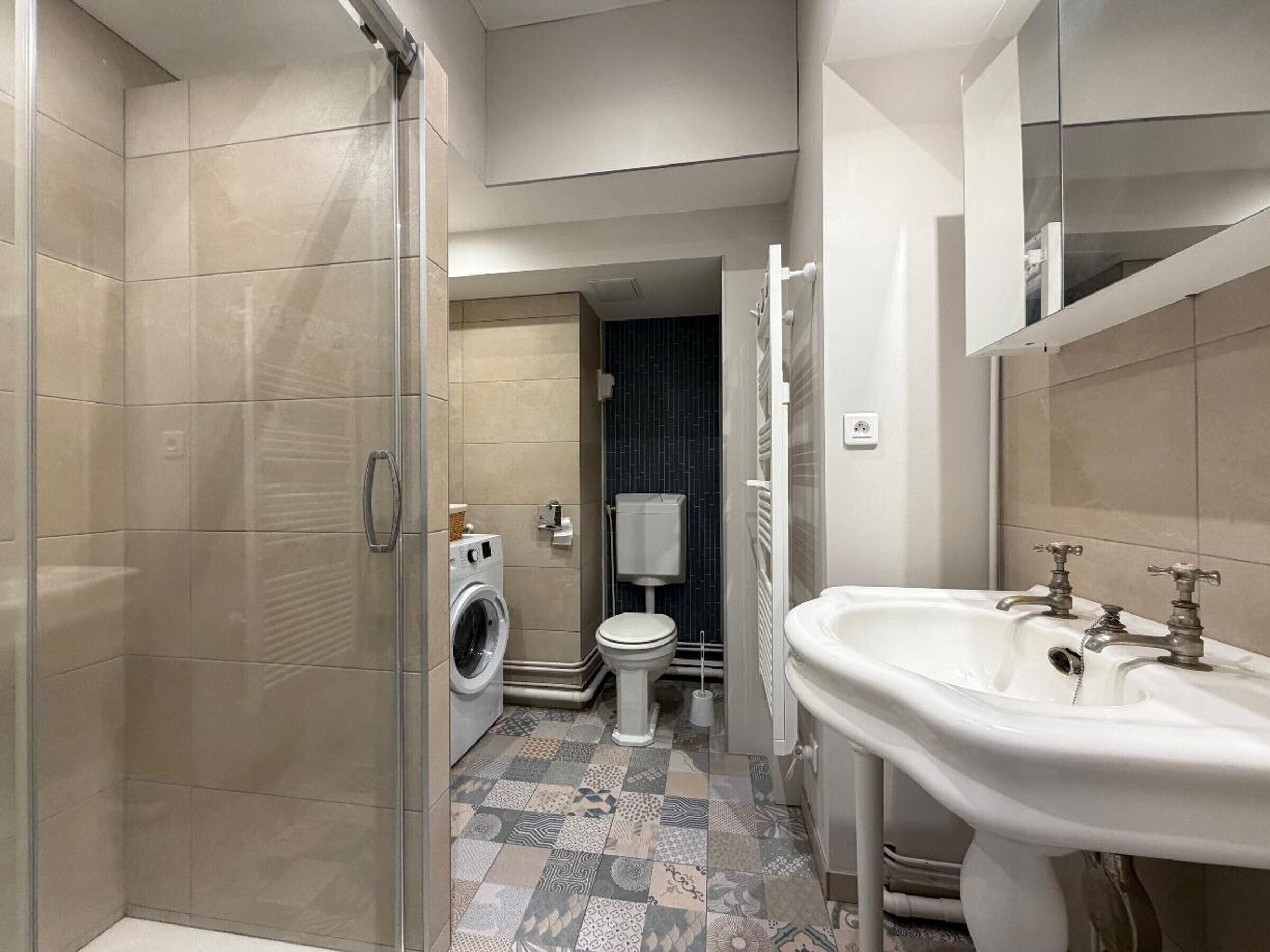 Une salle de bain moderne équipée d’une douche, de toilettes et d’un lave-linge.