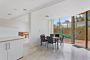 Una cocina moderna con armarios blancos y una zona de comedor con una mesa y sillas de vidrio.