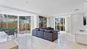 A spacious living area with a grey sectional sofa, a dining table with chairs, and a large sliding glass door leading to an outdoor patio.