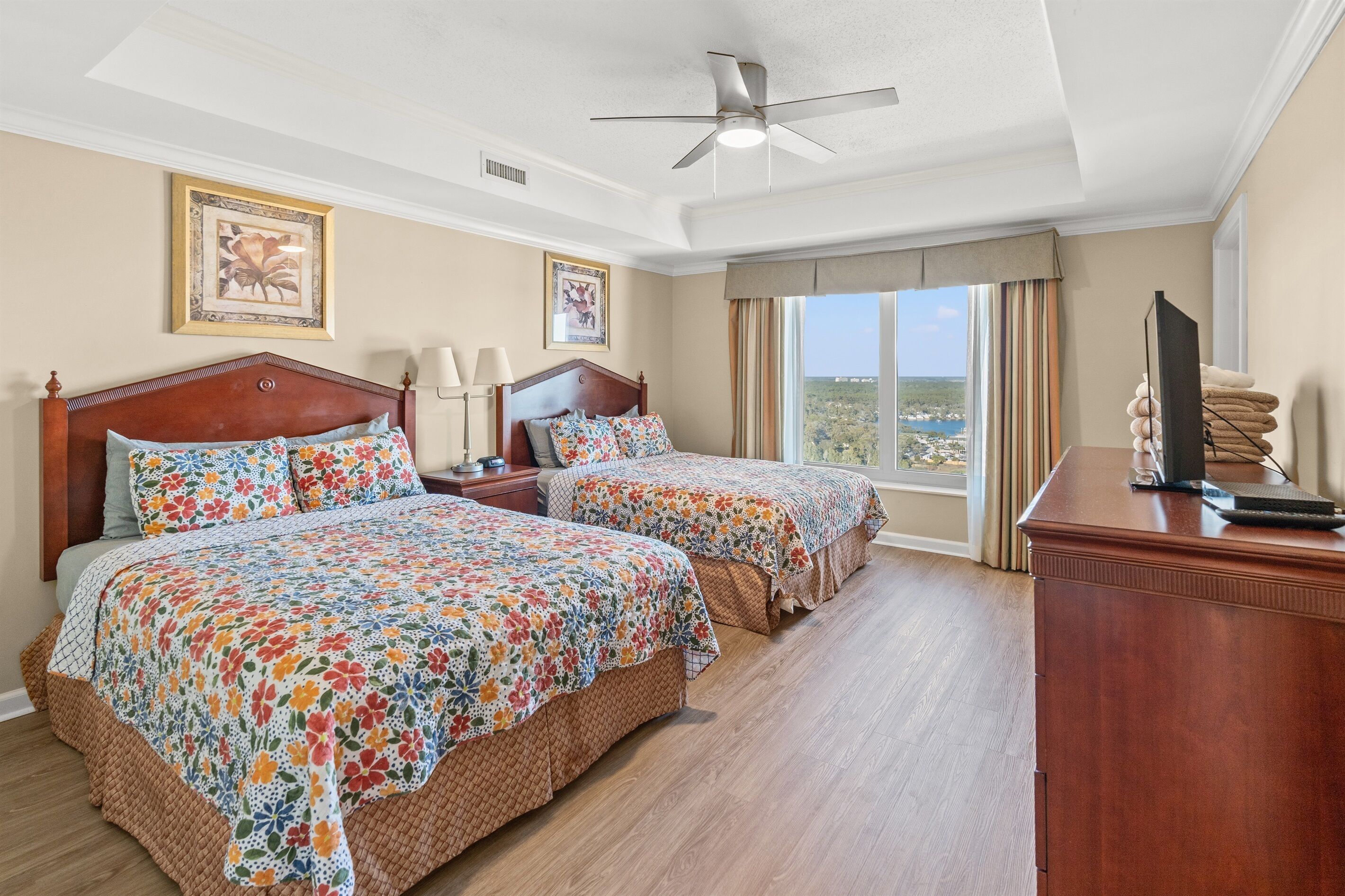 Habitación de hotel con dos camas, un escritorio, un televisor y vistas del paisaje.