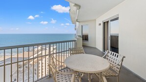 A balcony with a table and chairs, overlooking a beach and ocean. - Royale Palms 2305 2 Br Oceanview in Kingston, Pool (Myrtle Beach)
