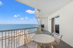 Enjoy the ocean view from this balcony with a round table and two chairs.