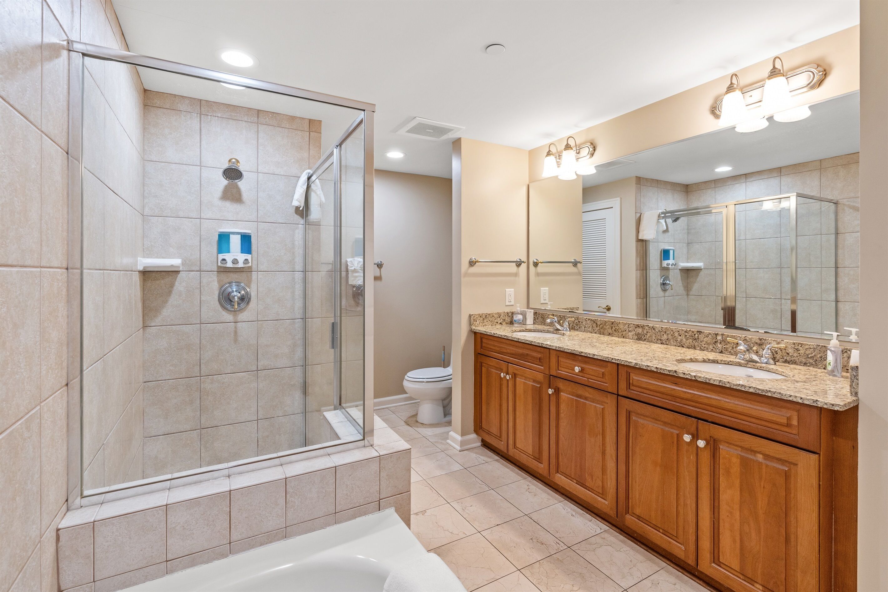 A modern bathroom with a glass-enclosed shower, a large vanity with a sink, and a mirror above the vanity.