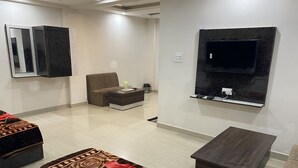 Ein modernes Wohnzimmer mit einer Couch, einem Couchtisch, einem an der Wand montierten Fernseher und einem gemusterten Teppich.