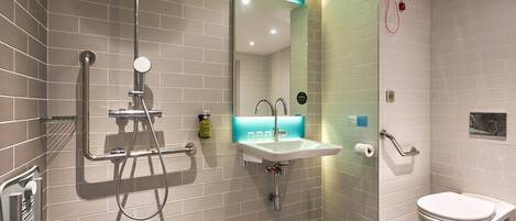 A modern bathroom with a shower, sink, and toilet.