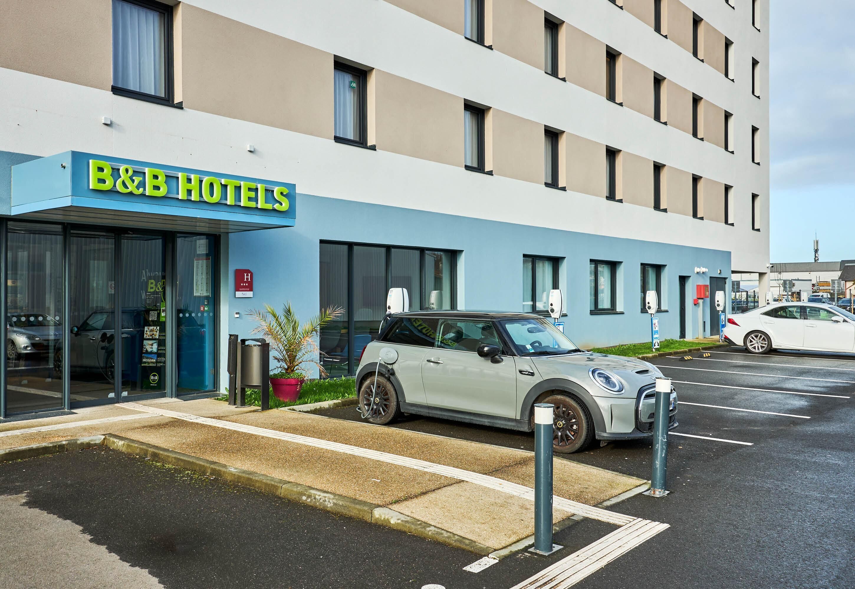 A B&B hotel with a modern facade, a parking lot, and a parked car.