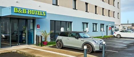 A B&B hotel with a modern facade, a parking lot, and a parked car.