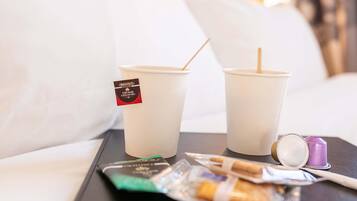 Two disposable cups with straws on a tray, a packet of cigarettes, and a lighter.