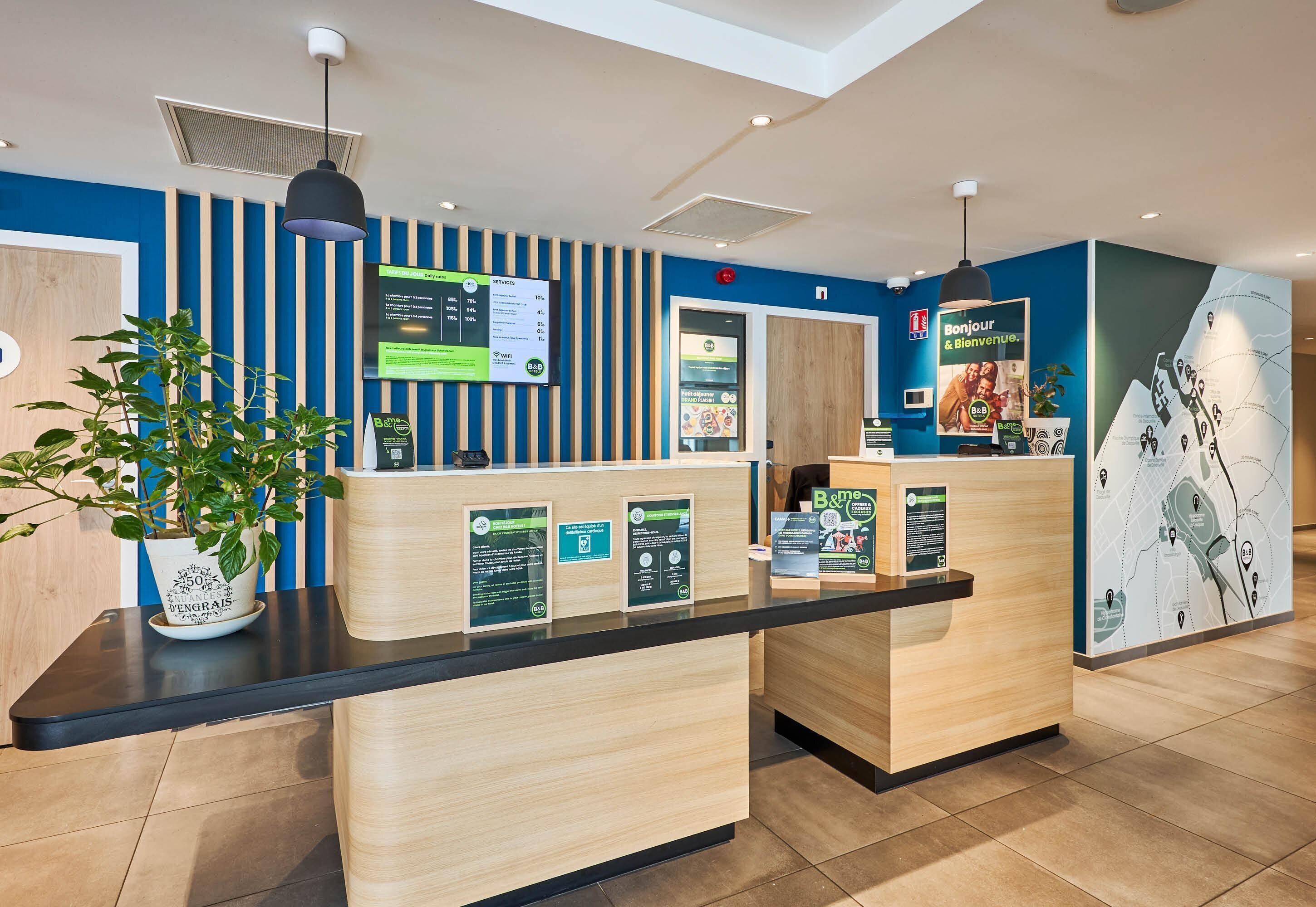 A reception desk with informational posters, a potted plant, and a map on the wall.