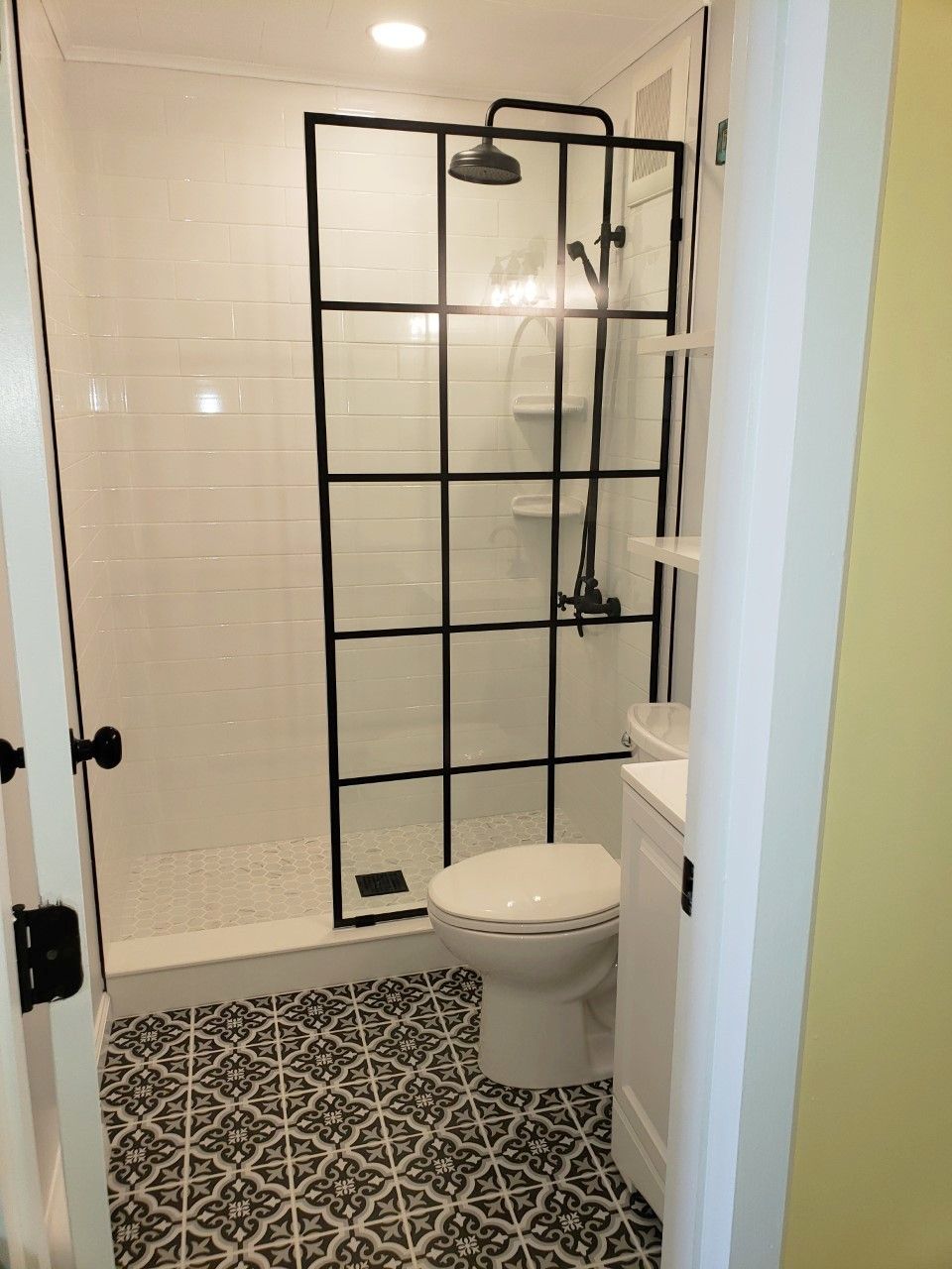 A bathroom with a shower enclosure, a toilet, and patterned floor tiles.