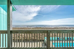 Enjoy breathtaking ocean views from this seaside deck, overlooking a sandy beach and pool area.
