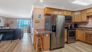 Eine moderne Küche mit Holzschränken, einem Edelstahlkühlschrank und einer Mikrowelle.