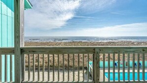 Eine Holzterrasse mit Blick auf den Ozean und den Strand.