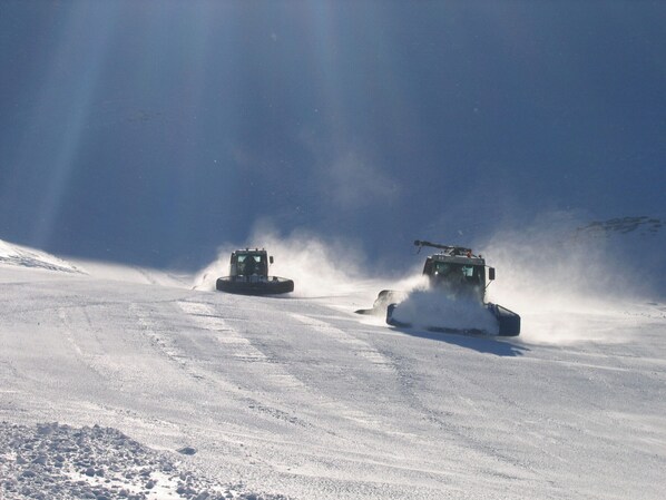 Two snow grooming machines on a snow-covered slope.