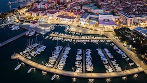 A marina with numerous boats docked, a cityscape with buildings, and a large container port in the background. - Villa Lavanda in Kriz Sezana With Private Swimpool (Sezana)