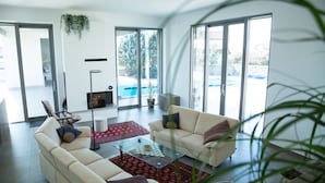 A modern living room with two sofas, a glass coffee table, and a red patterned rug. There is a large window providing a view of the outdoors. - Villa Lavanda in Kriz Sezana With Private Swimpool (Sezana)