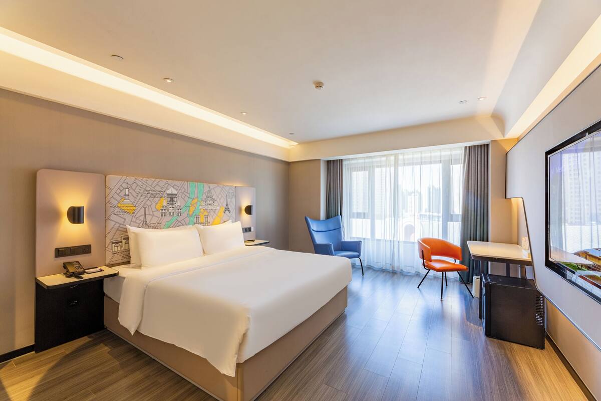 Ein modernes Hotelzimmer mit einem großen Bett, einem Schreibtisch und einem Sessel.