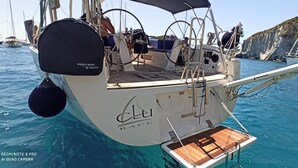Eine Segelyacht mit Holldeck, genannt 'CLU RACE', liegt an den felsigen Klippen festgemacht.
