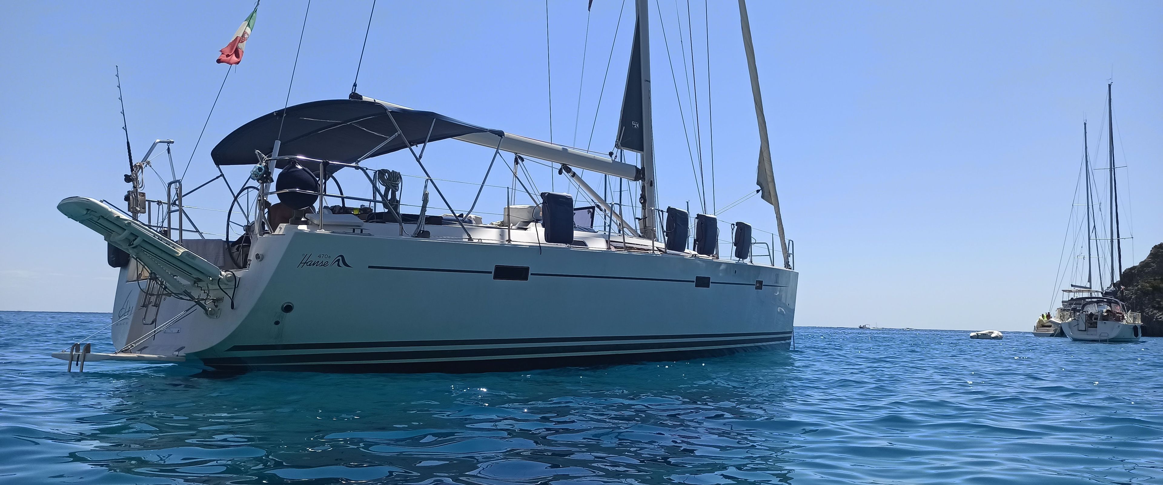 A large sailboat with a covered deck and multiple masts, floating on calm blue waters.