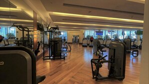 Une salle de sport spacieuse, dotée de divers appareils d’exercice, de grandes fenêtres et d’un plancher en bois.