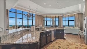 A spacious kitchen with a large island, dark cabinetry, and a view of the ocean through large windows.