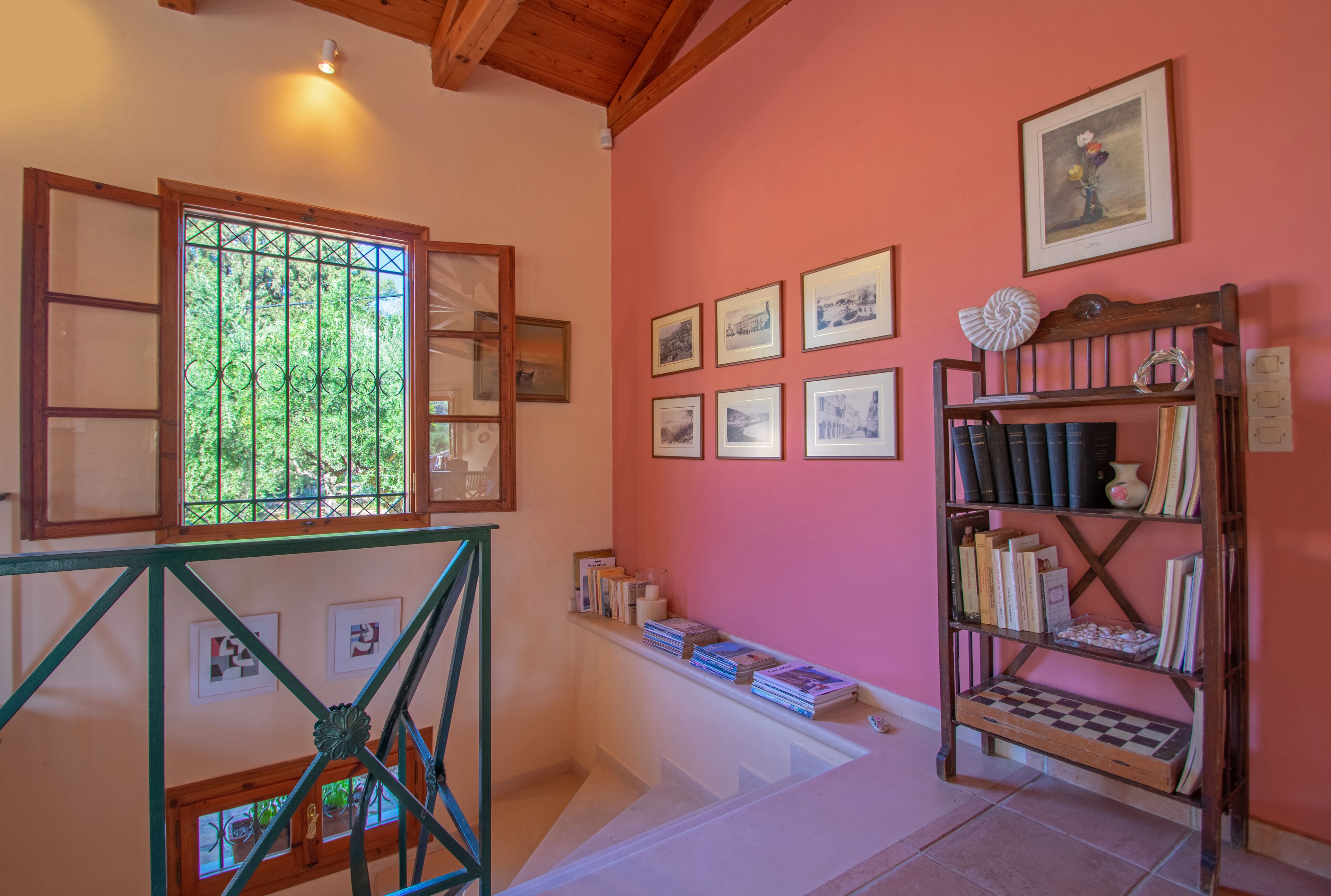 Une pièce avec un escalier, une bibliothèque et des tableaux encadrés accrochés au mur.