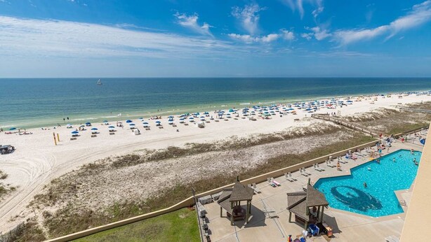 A beach resort with a large pool, beach umbrellas, and a lifeguard tower. - New to the Rental Market, New Owner, Newly Renovated!!! (Orange Beach)