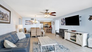A living room with a sofa, dining table, chairs, a TV, and a ceiling fan. - New to the Rental Market, Newly Owner, Newly Renovated!!! (Orange Beach)