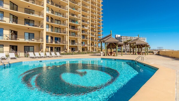Un hotel con una piscina grande, varios balcones y zonas de estar al aire libre.