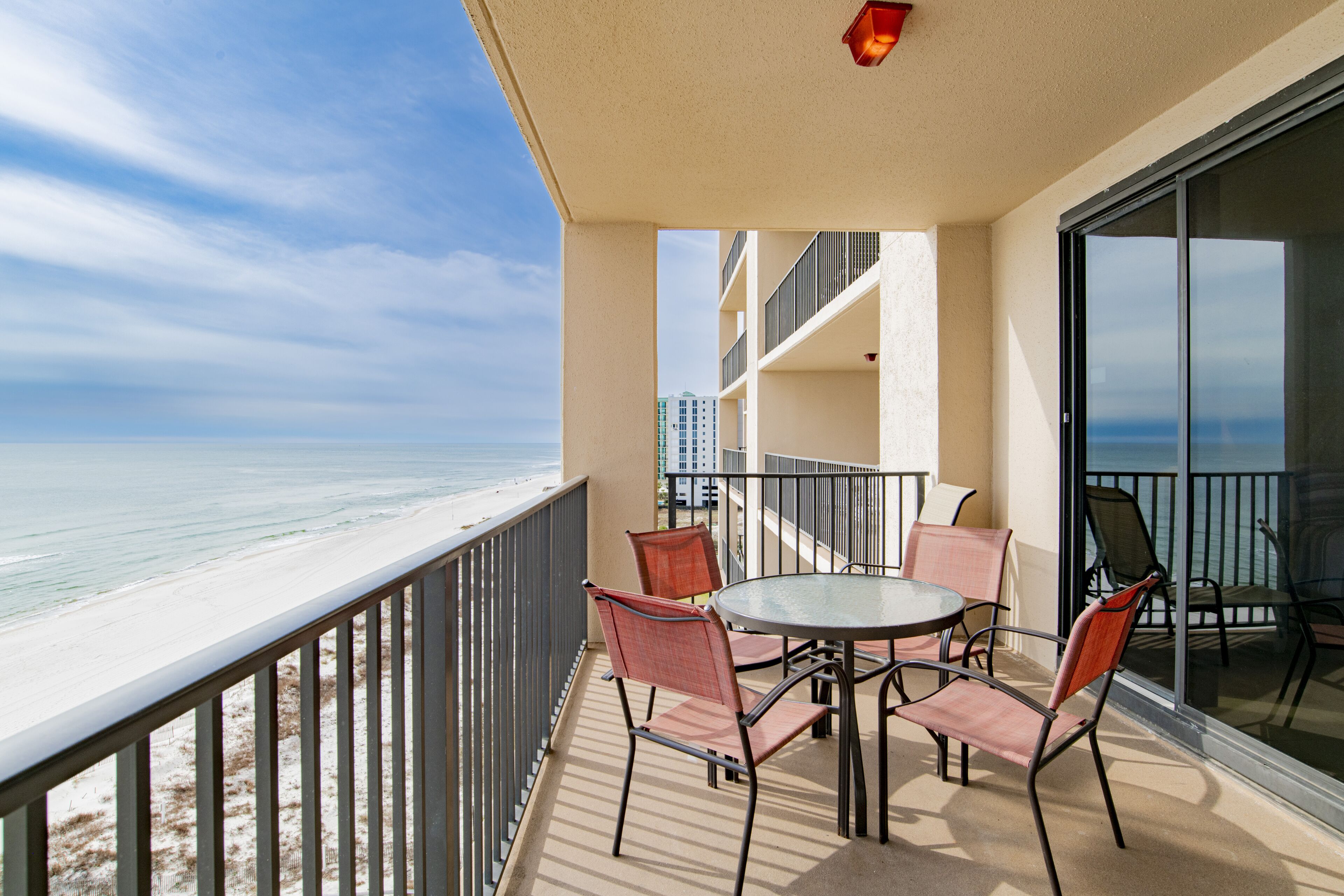 A balcony with a table and chairs overlooking a beach.