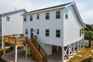 A two-story house with a wooden deck and a staircase leading to a front door.