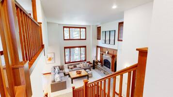 A spacious living area with a fireplace, a sofa set, and a staircase with wooden railings.