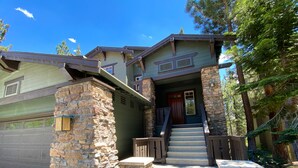 A two-story house with a stone facade, a front porch with steps, and a garage. - Timbers 6 Updated and Pet-Friendly, Private Jacuzzi, Private Garage by RedAwning (Mammoth Lakes)