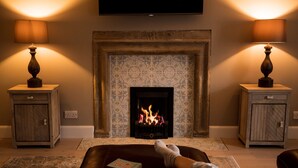 A cozy living room with a fireplace, two lamps, a sofa, and a book.