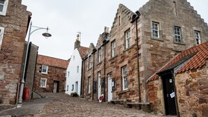 A cobblestone street lined with historic stone buildings, some with visible signage and windows.