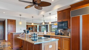 A spacious kitchen with wooden cabinets, granite countertops, and a central island.