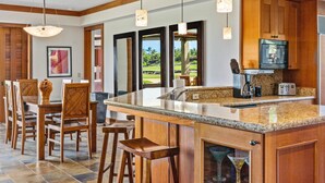 A spacious kitchen with wooden cabinetry, a granite countertop, and a large island with bar stools.