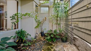 A small, enclosed outdoor space with a variety of potted plants, a stone pathway, and a built-in bench.