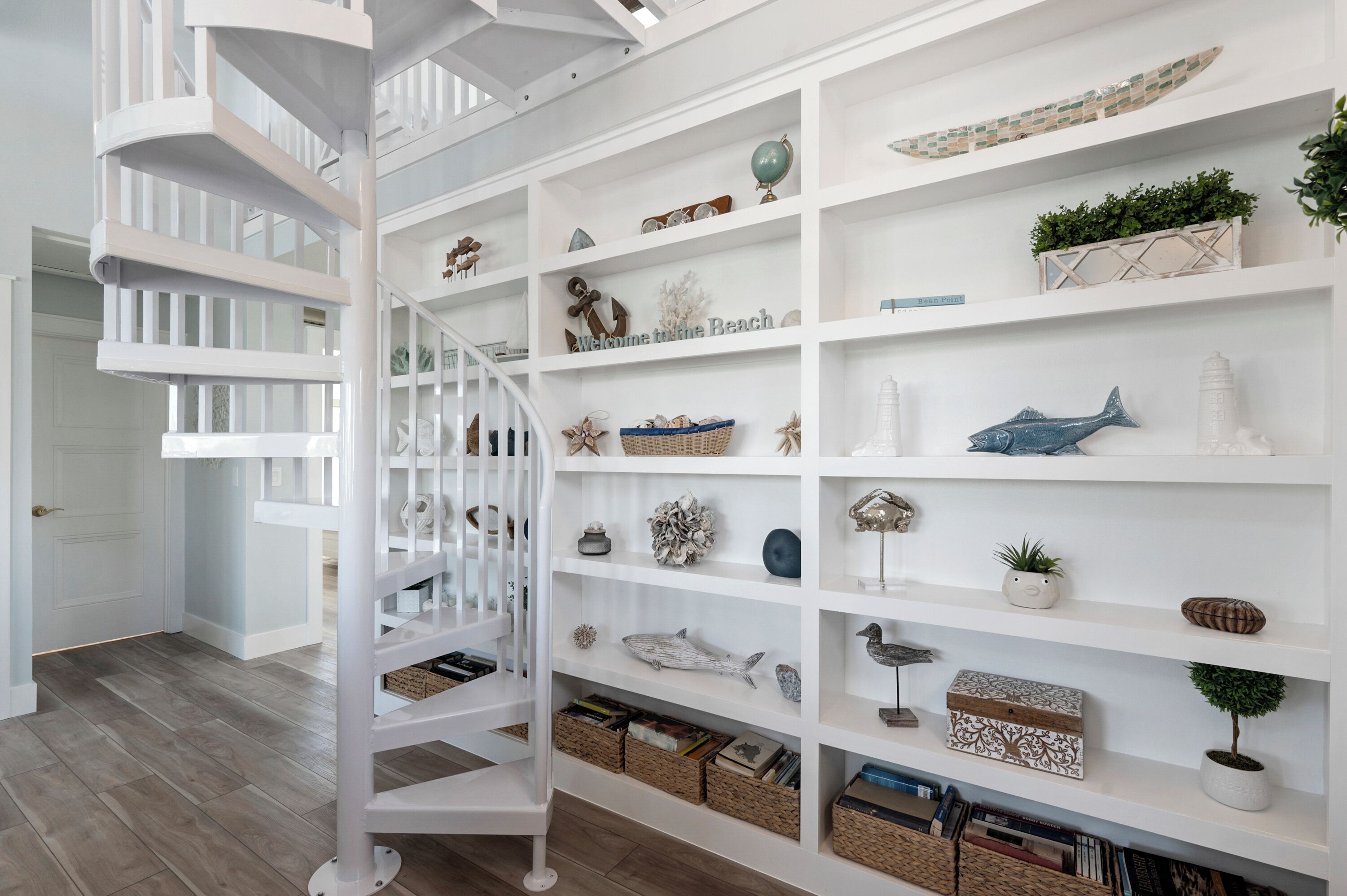 Un escalier en colimaçon blanc mène à une étagère à plusieurs niveaux, où sont disposés divers objets décoratifs et des paniers.
