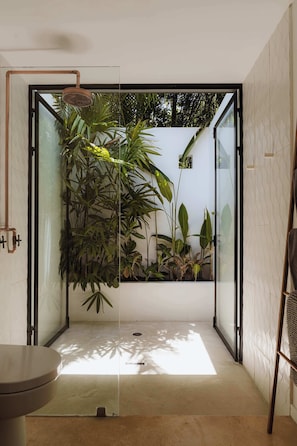 Un baño moderno con cabina de ducha de vidrio, inodoro y varias plantas.