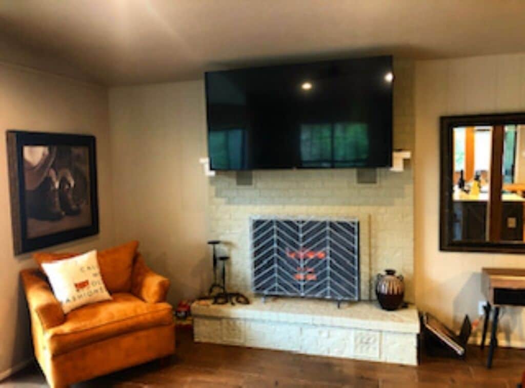 Un salón con chimenea, televisor montado y sofá.