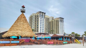 Ein Restaurant direkt am Strand, mit einem strohgedeckten Gebäude, einer Holzterrasse und einem Schild mit der Aufschrift 'Old Drinks Oyster'.