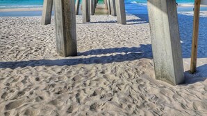Eine Holzsteg, der sich ins Meer erstreckt, mit freiem Blick auf Strand und das Meer.