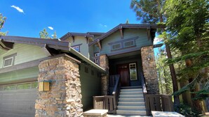 A two-story house with a stone facade, a front porch with steps, and a garage. - Pet-Friendly, Bright, Updated & On Golf Course! Private Game Room and Hot Tub (Mammoth Lakes)
