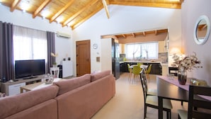 A living room with a sofa, TV, and dining area with chairs and a table. - Villa Bella Luna (Zakynthos)