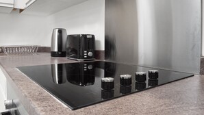 A modern kitchen with a black induction cooktop, stainless steel appliances, and a granite countertop.