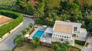 Uma casa moderna com piscina, um pátio e vista para o verde ao redor.