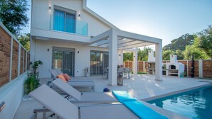 Uma casa moderna de dois andares com piscina, área de estar externa e churrasqueira.