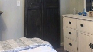 A bedroom with a bed, a dresser, a mirror, and a dark wooden door. - Hometown Haven in Glens Falls, NY (between Lake George & Saratoga) (Glens Falls)