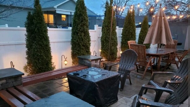 An outdoor patio area with stone tables, chairs, and a fire pit. - Hometown Haven in Glens Falls, NY (between Lake George & Saratoga) (Glens Falls)